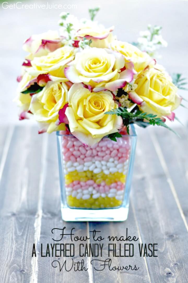 Hermoso jarrón lleno de dulces en capas de bricolaje con flores